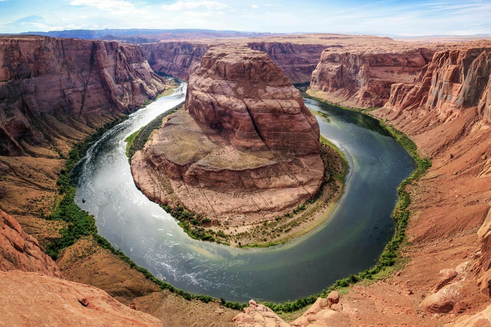 The Colorado River curving in a horseshoe around a sandstone butte in a red rock canyon