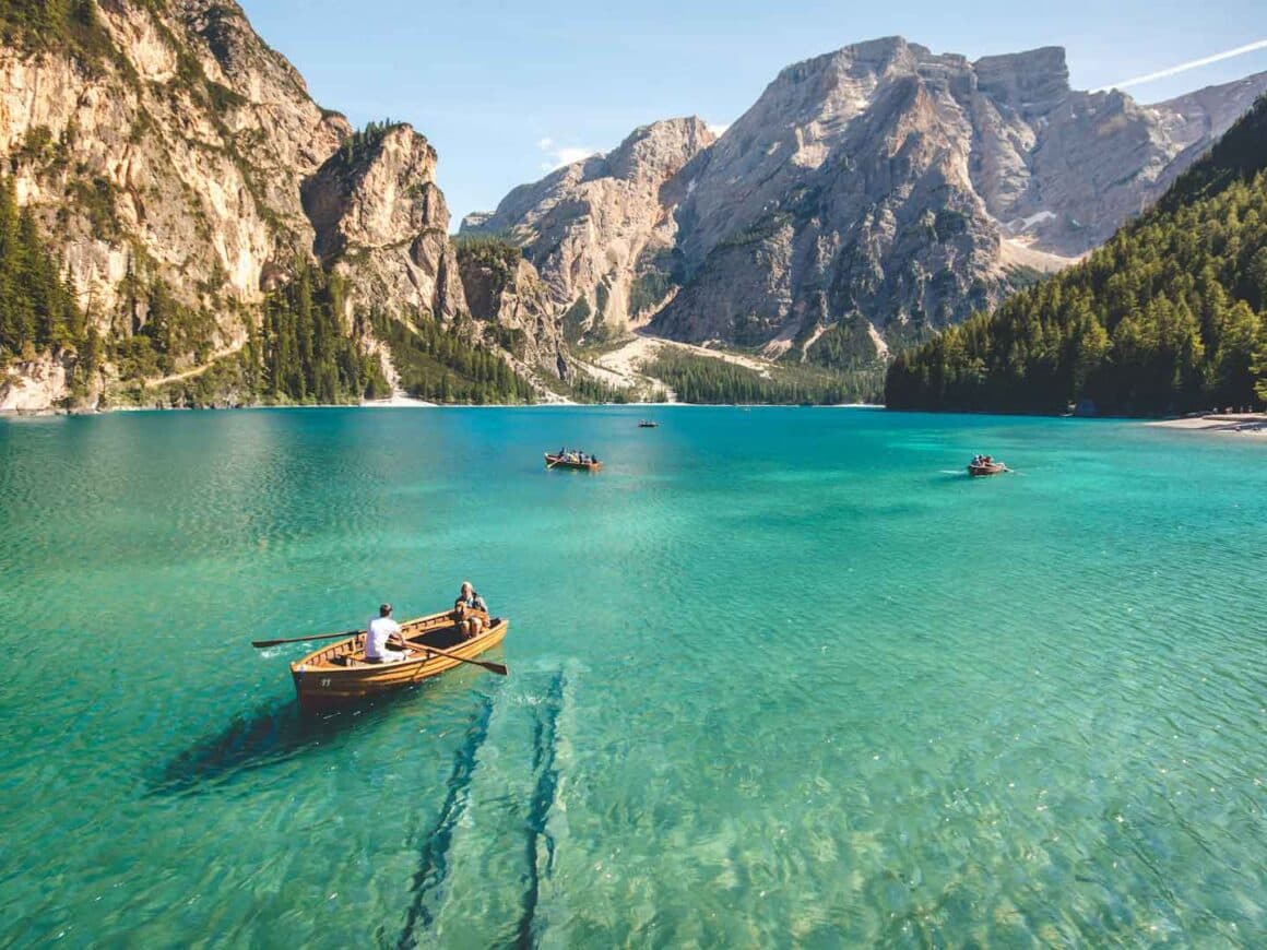 Wooden rowboats on a turquoise alpine lake ringed by pine forest and limestone peaks
